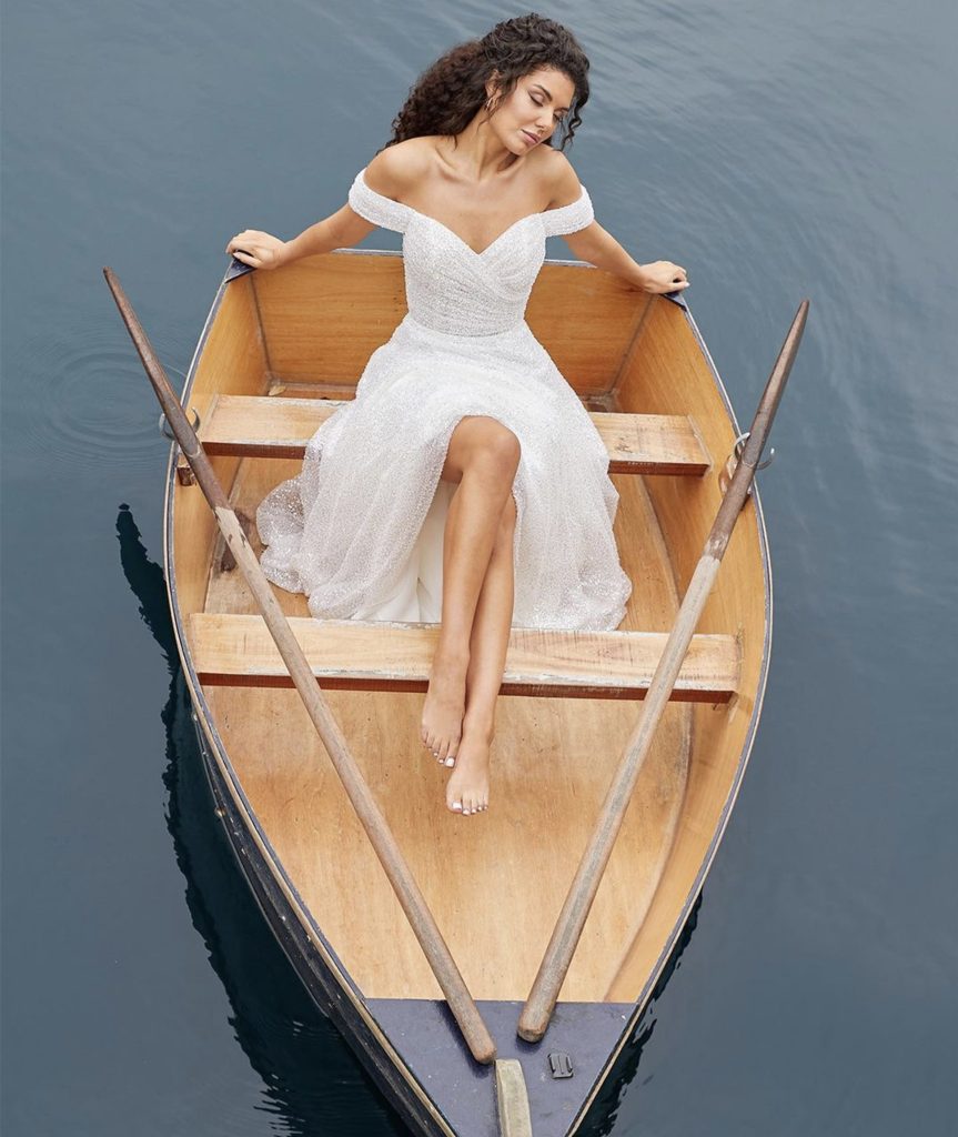 Bride in wedding dress sitting in a boat by Liz Patey